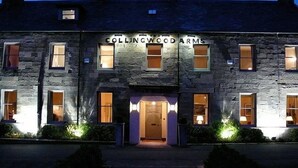 A stone building with the sign "Collingwood Arms" at the entrance, featuring multiple windows and a well-lit facade. - The Collingwood Arms Hotel (Cornhill on Tweed)