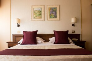 A neatly made bed with two pillows, a wooden headboard, and two wall-mounted lamps.