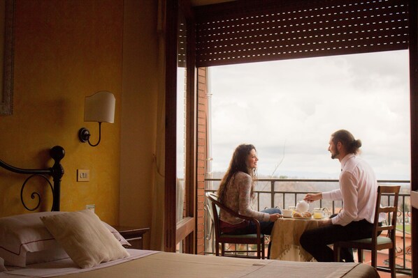 A room with a bed, a table with breakfast items, and a view through a window.