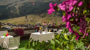 A terrace with tables and chairs, overlooking a mountainous landscape. - Hotel Parè (Livigno)