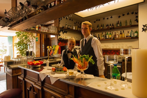 Un espace bar avec un comptoir, des étagères remplies de bouteilles et un plafond décoratif.