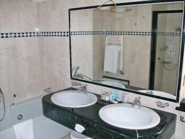 Un baño con dos lavamanos, un espejo grande y una bañera.