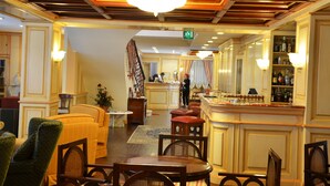 A hotel lobby with a bar area, seating arrangements, and a reception desk. - Hotel De la Ville (Saint-Vincent)