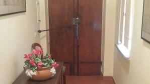 A hallway with a wooden door, a patterned rug, a bench with a green cushion, and a decorative wall piece. - Navona Nice Room (Rome)