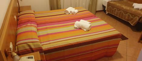 A hotel room with a large bed, a smaller bed, a bedside table with a phone, and a window with curtains.
