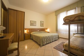 Habitación de hotel con cama, escritorio con silla, armario y dos lámparas de noche.