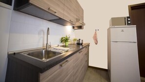 A modern kitchen with a stainless steel sink, wooden cabinets, a built-in oven, and a white refrigerator. - Piccola Oasi (Vigonza)