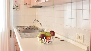 A kitchen with wooden cabinets, a white countertop, and a fruit bowl. - Piccola Oasi (Vigonza)