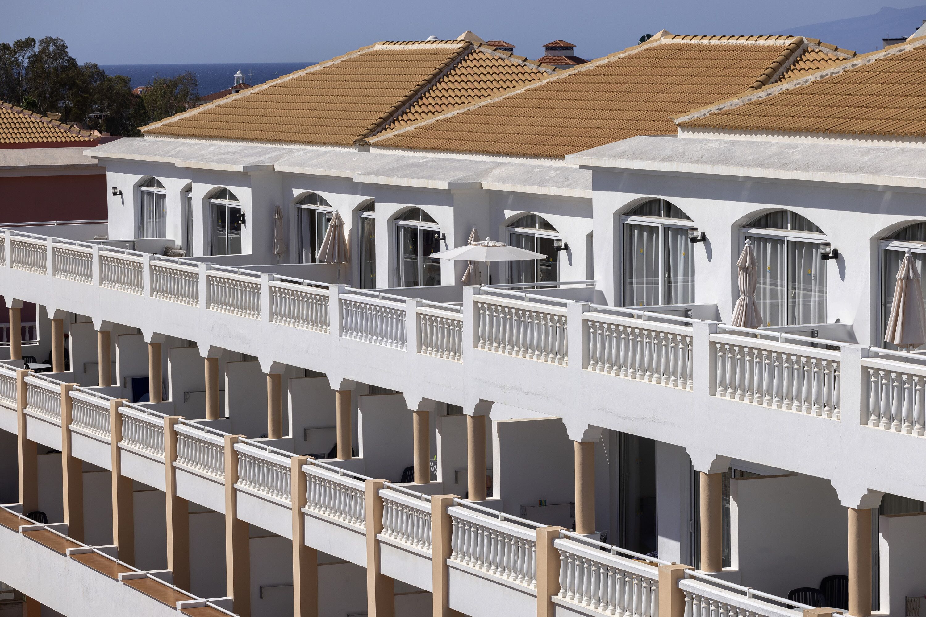 A multi-story hotel with white exterior walls and terracotta roof tiles.