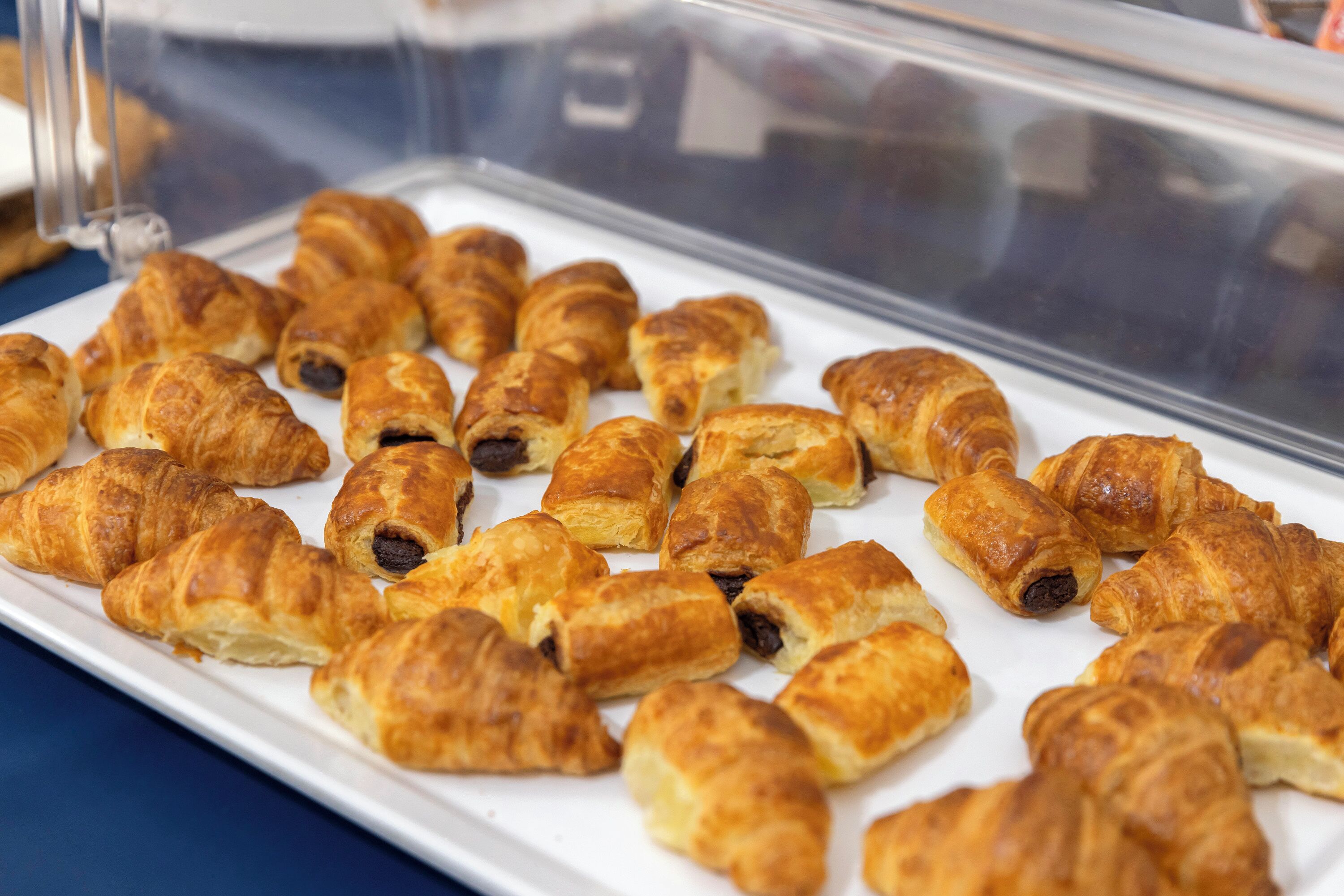 Ett vitrinskåp med ett urval av bakverk, inklusive croissanter och bakverk fyllda med choklad.