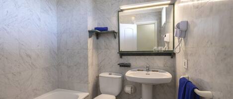 A bathroom with a bathtub, toilet, sink, and a hairdryer on the wall.