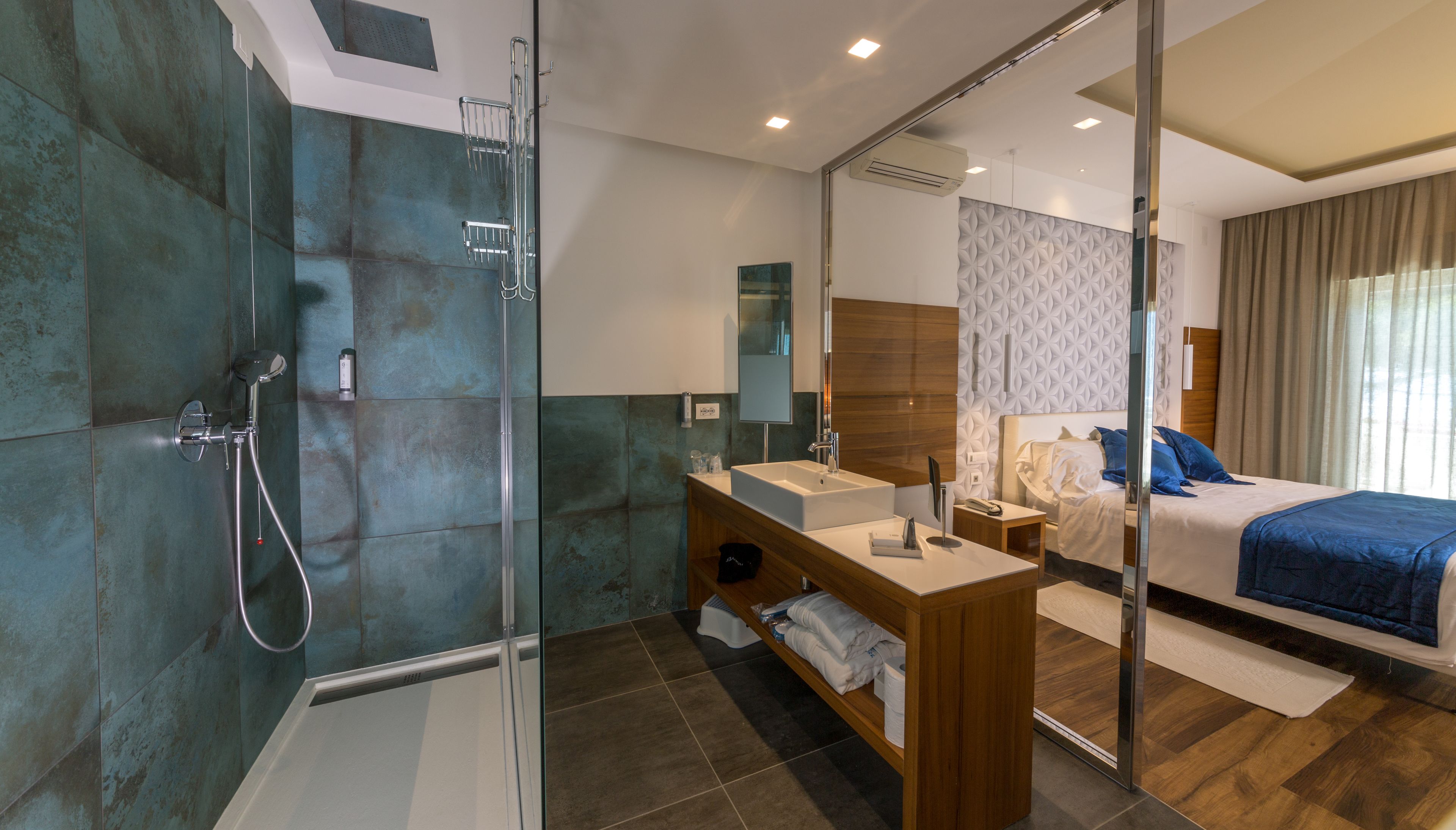 A modern bathroom with a glass shower enclosure, a wooden vanity with a sink, and a large mirror.