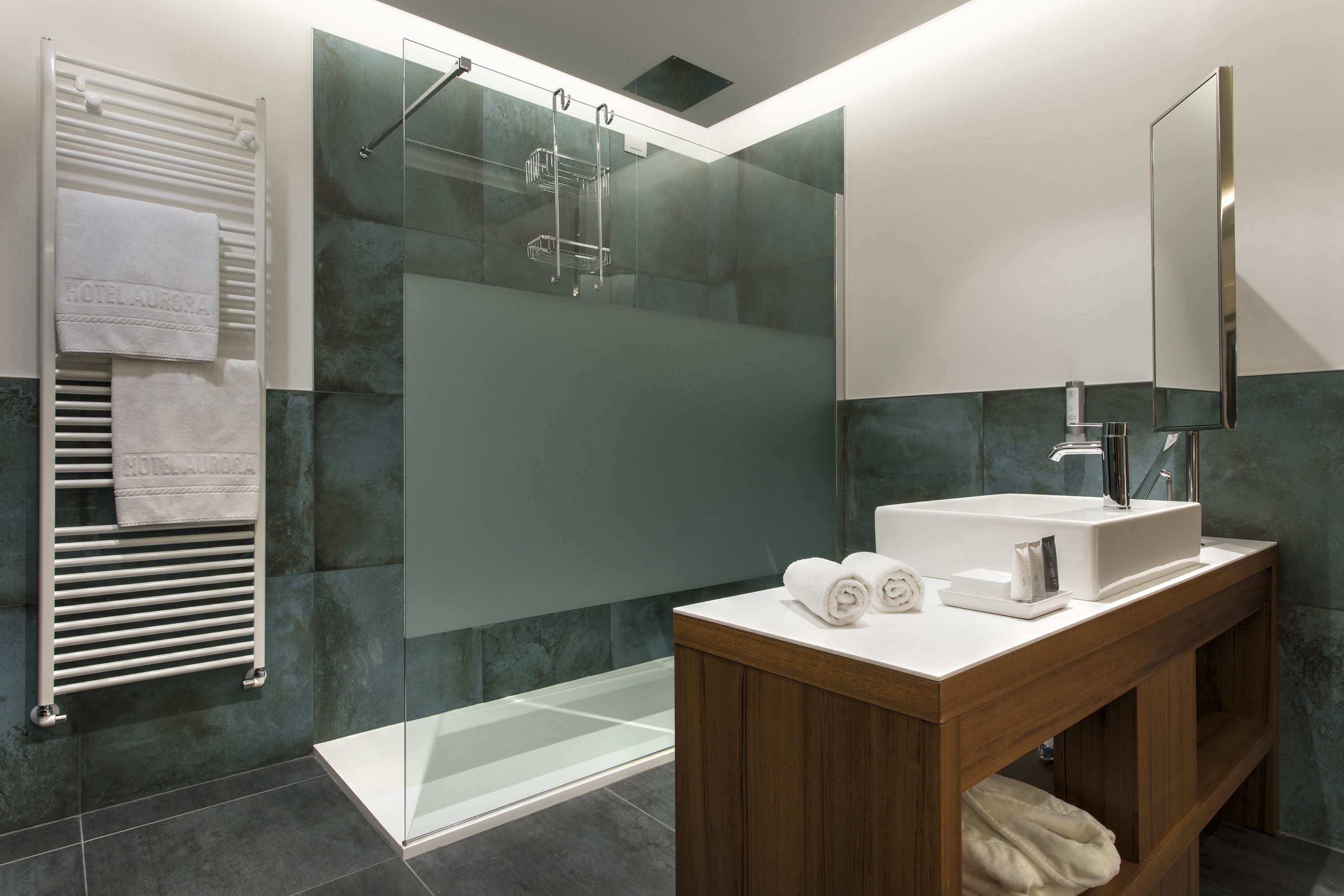 Un bagno moderno con cabina doccia in vetro, un mobile bagno in legno con lavandino e uno specchio grande.