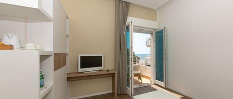 Een moderne hotelkamer met een houten vloer, een flatscreen televisie, een tafeltje en een balkon met uitzicht.