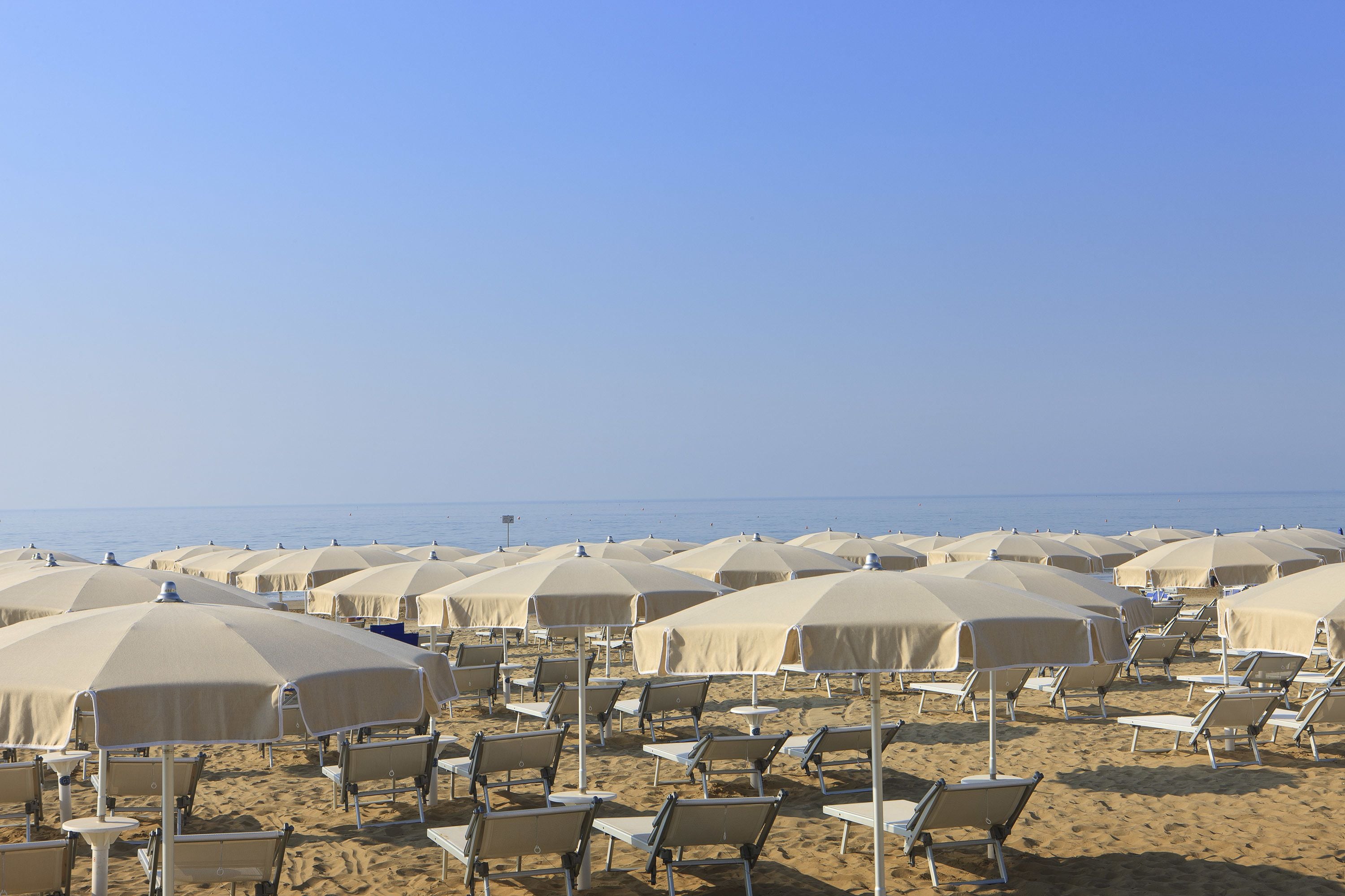 A beach with rows of sun umbrellas and lounge chairs.