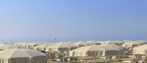 A beach with rows of sun umbrellas and lounge chairs.