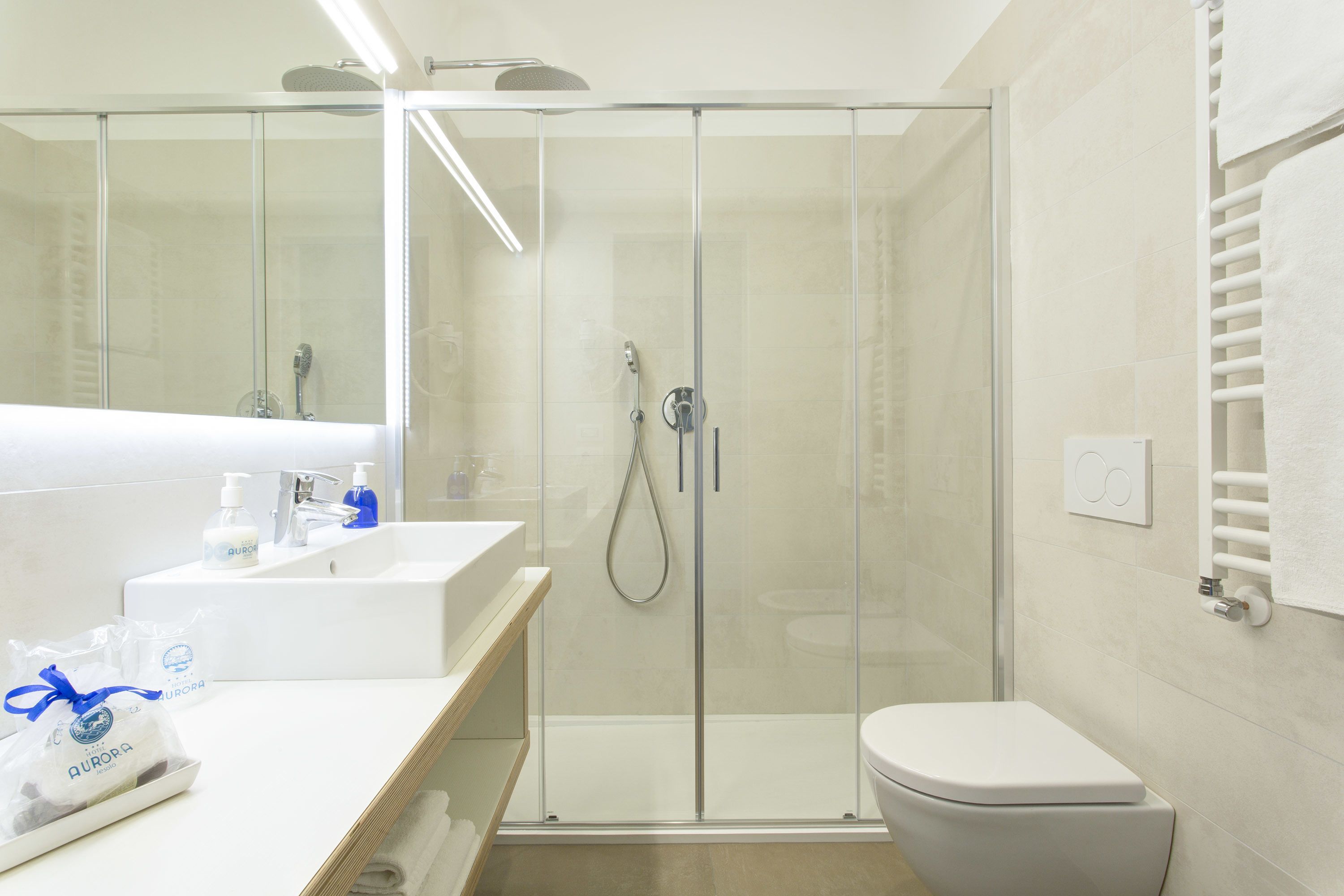 Un baño moderno con ducha de vidrio, un lavabo blanco con espejo y un inodoro.