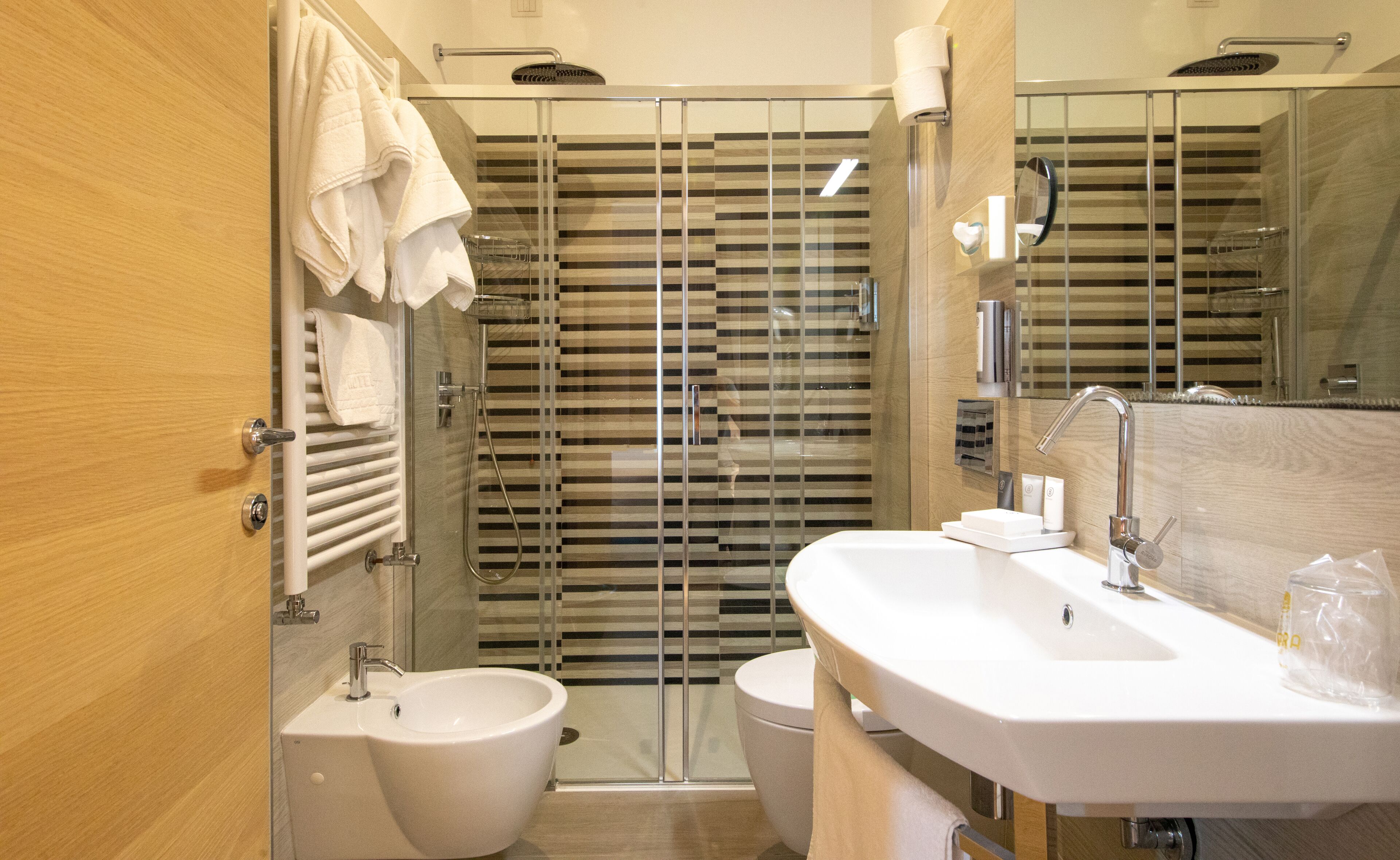 Une salle de bain moderne équipée d’un bidet, de toilettes et d’une douche à l’italienne.
