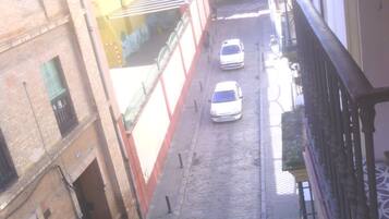 Una estrecha calle adoquinada con dos coches estacionados al borde.
