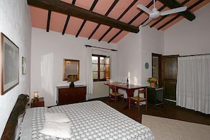 Une chambre à coucher avec un lit, un bureau, une chaise, un miroir et une fenêtre.