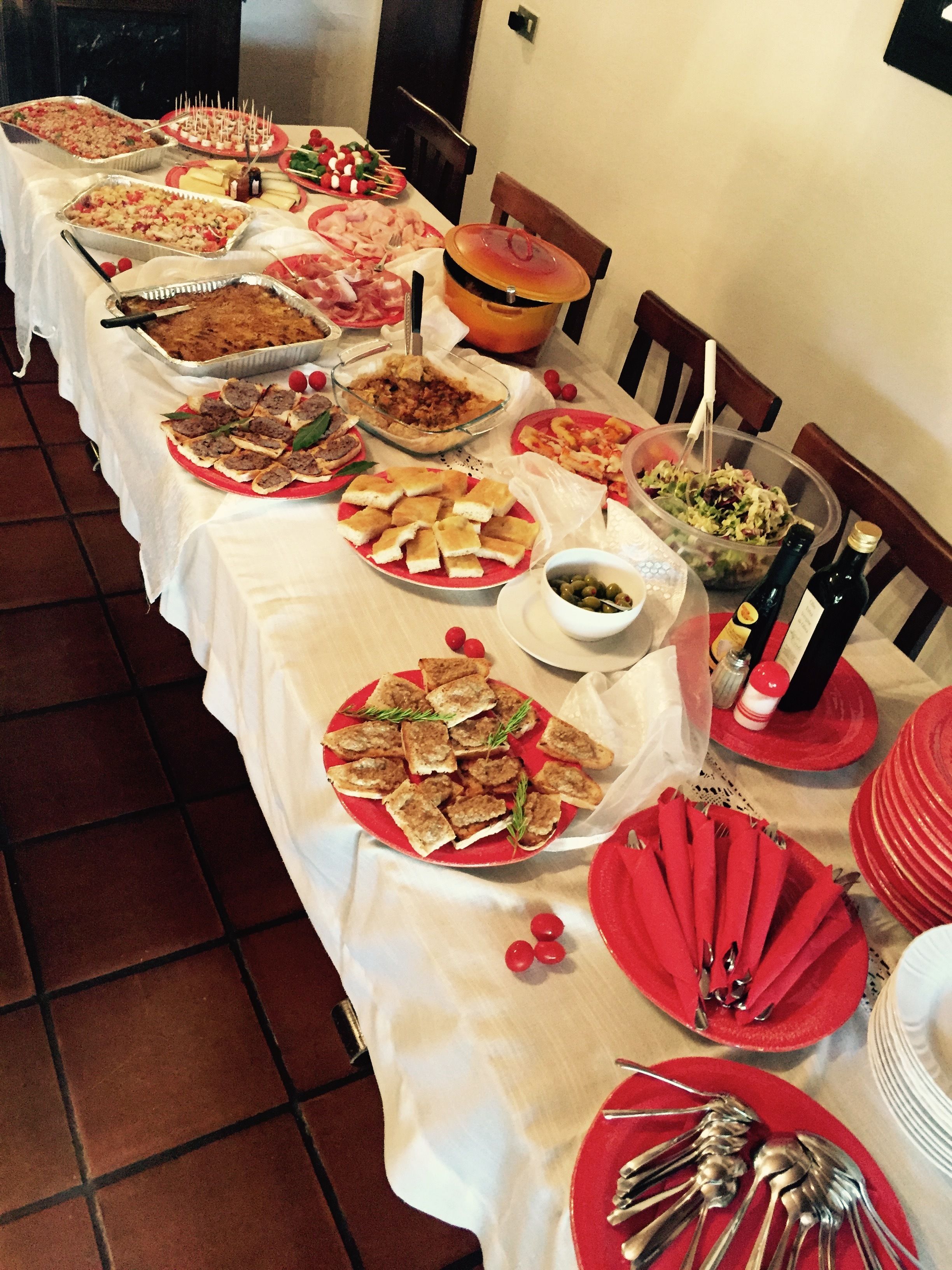 Een lange tafel vol met verschillende soorten eten en gerechten, waaronder een grote pan, kommen en borden met eten.