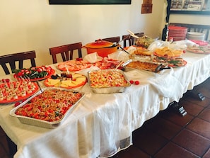 Une table de buffet garnie de différents plats et sur laquelle est posée une grande marmite.