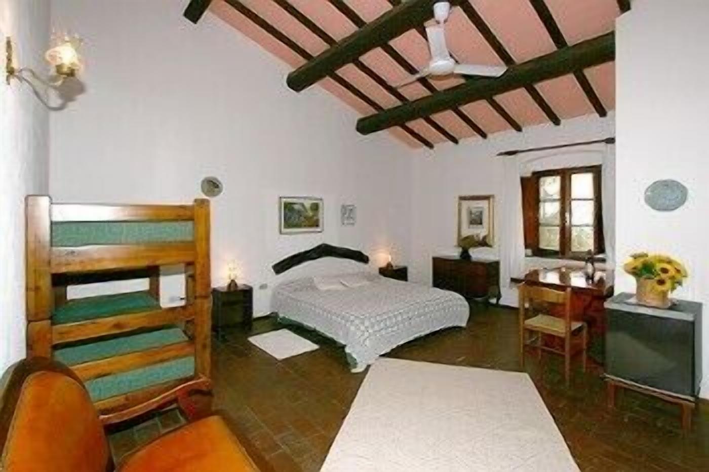 Une chambre à coucher comprenant un lit, un bureau, une chaise, une fenêtre et un ventilateur de plafond.