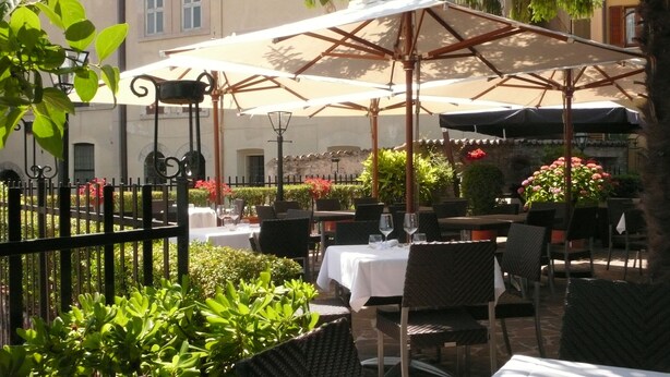 An outdoor patio with tables and chairs, surrounded by greenery and a fence. - Il Panciolle (Spoleto)