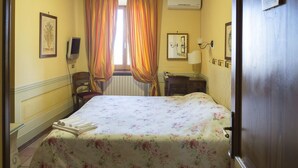 A hotel room with a bed, a chair, a desk, a lamp, and a window with curtains. - Il Panciolle (Spoleto)
