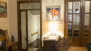 A lobby with a wooden ceiling, tiled floor, a table with magazines, a lamp, and a door labeled "RISTORA". - Il Panciolle (Spoleto)