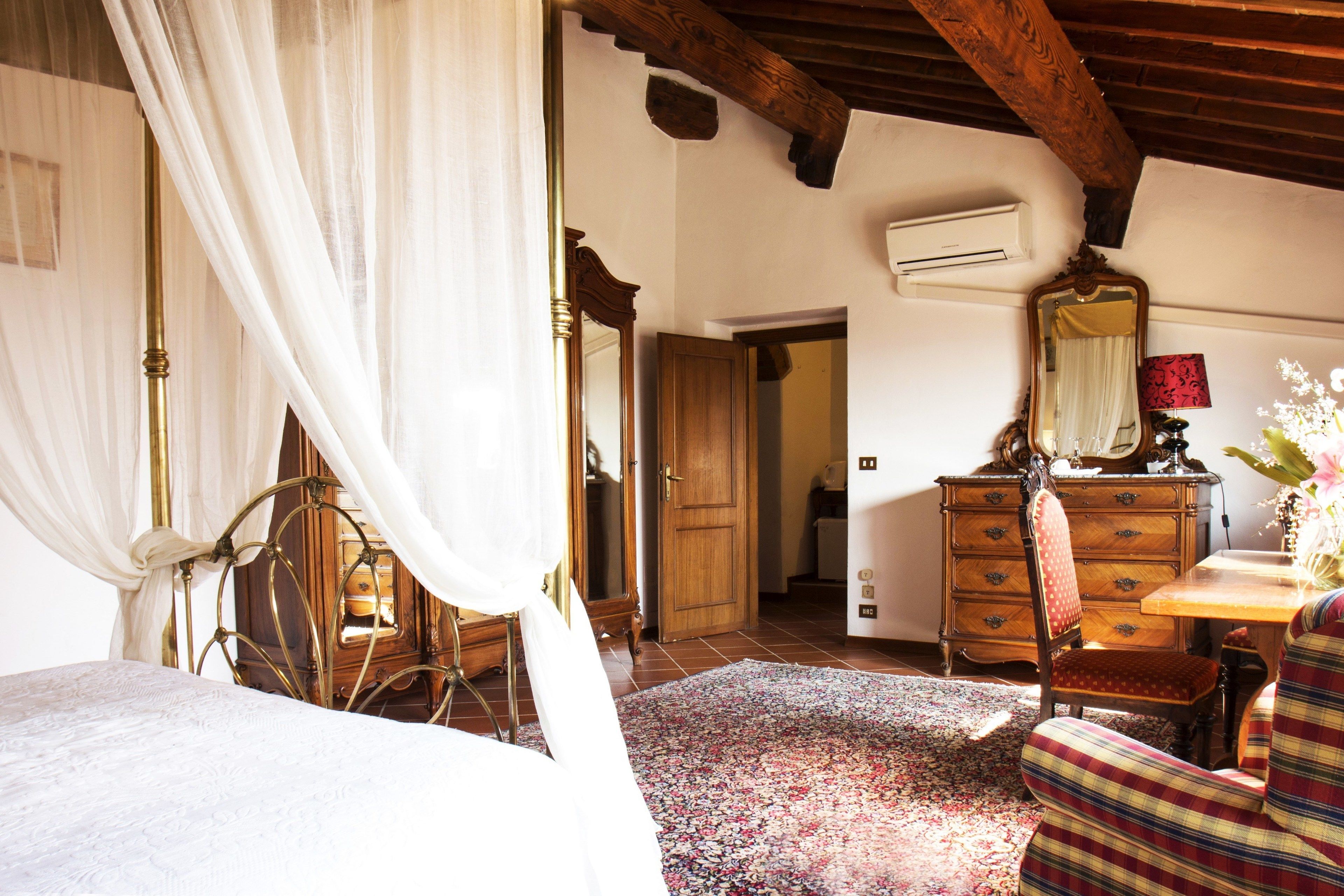 Un dormitorio con cama de dosel, muebles de madera y alfombra estampada.