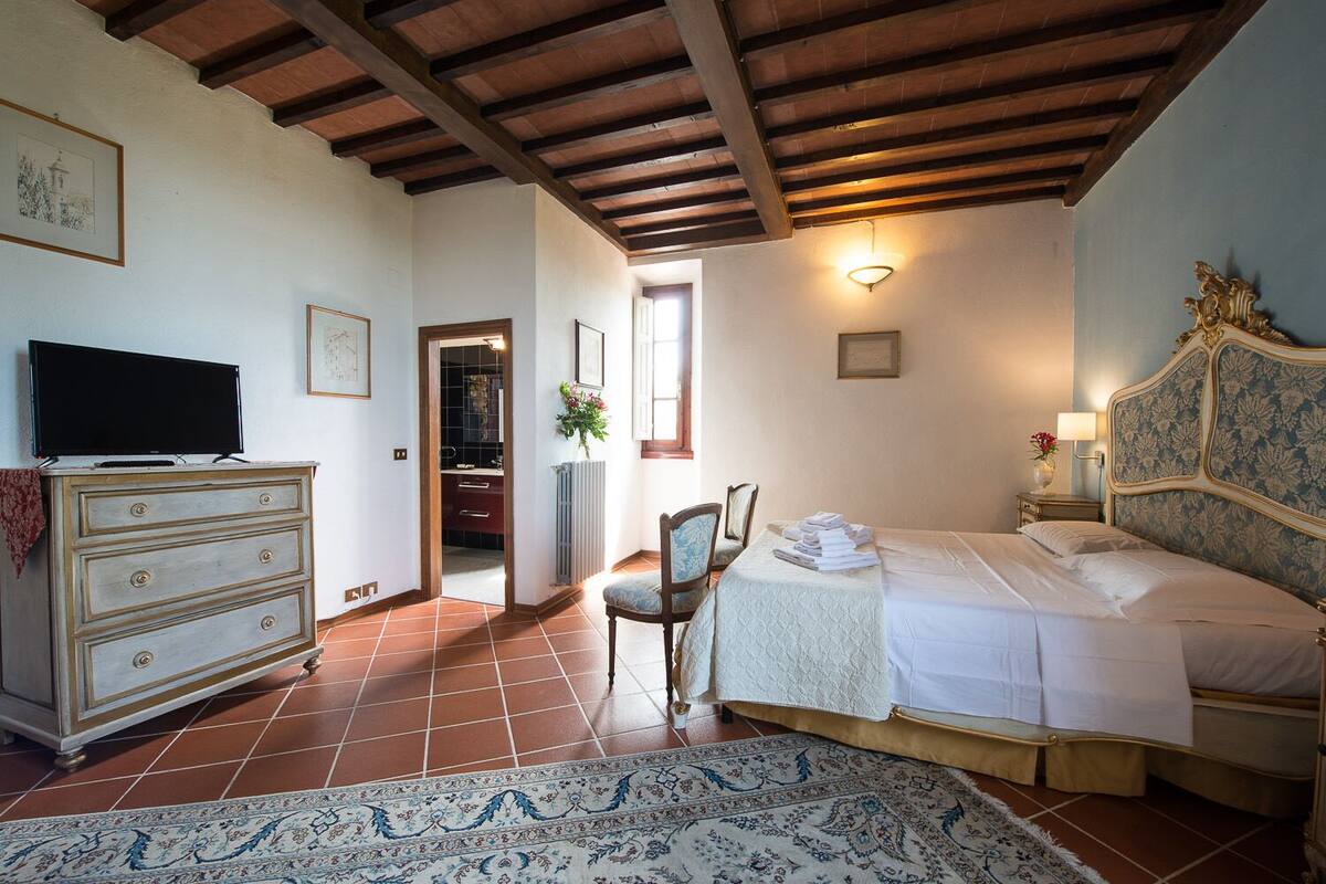 Une chambre à coucher avec un lit, une commode, une télévision et une chaise.