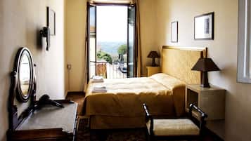 Une chambre d’hôtel équipée d’un lit, d’une chaise, d’un bureau, d’un miroir, d’une lampe et offrant une vue sur l’extérieur.