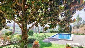 Ein Poolbereich mit Blick auf eine hügelige Landschaft, umgeben von Grünflächen und Gartenmöbeln.