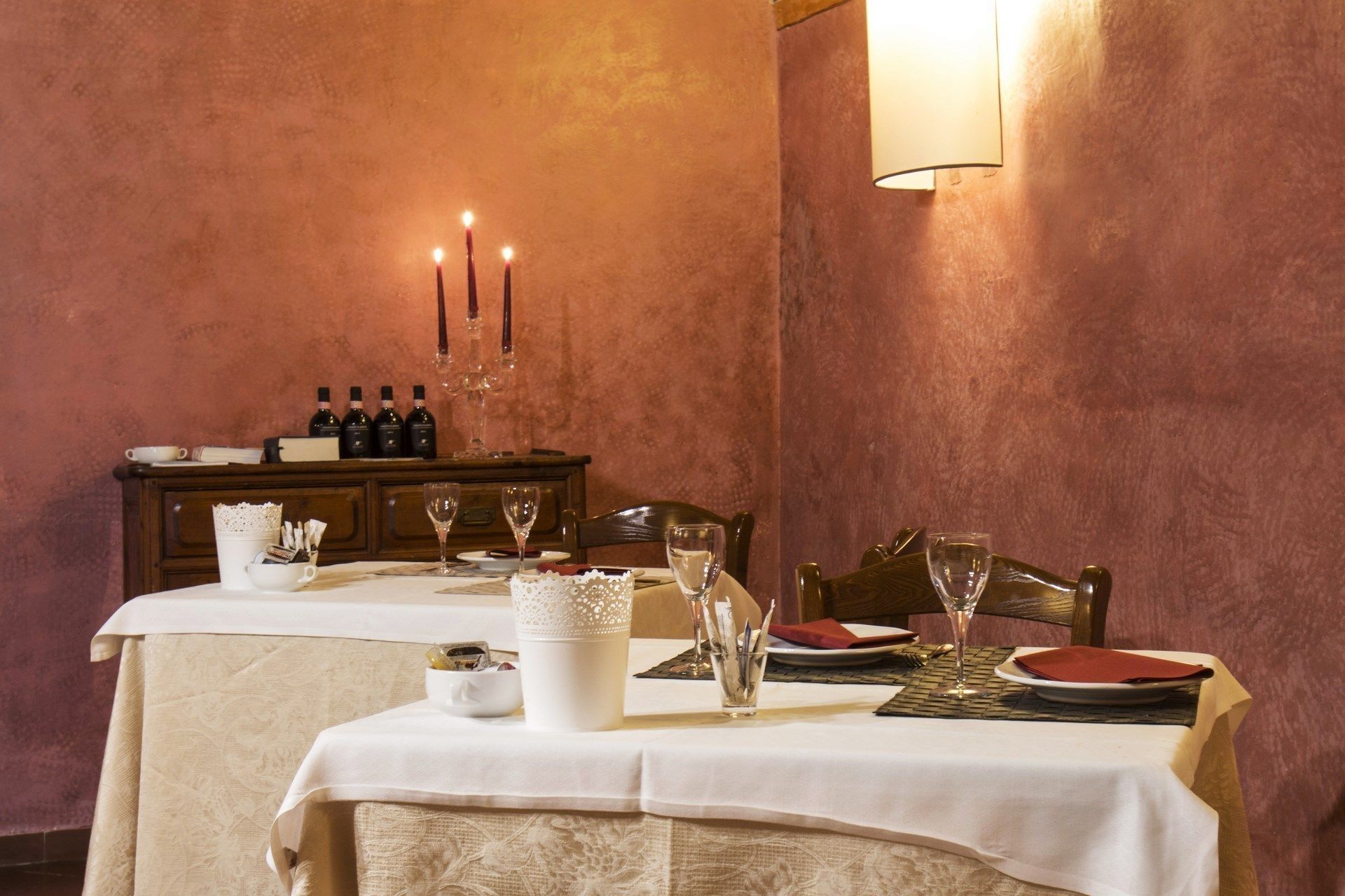 Una mesa de comedor con mantel blanco, copas de vino y un candelabro.