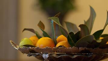 A silver tray with oranges and green leaves on a reflective surface.