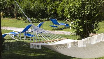 Relax in a serene outdoor oasis with a hammock and lounge chairs surrounded by lush greenery.