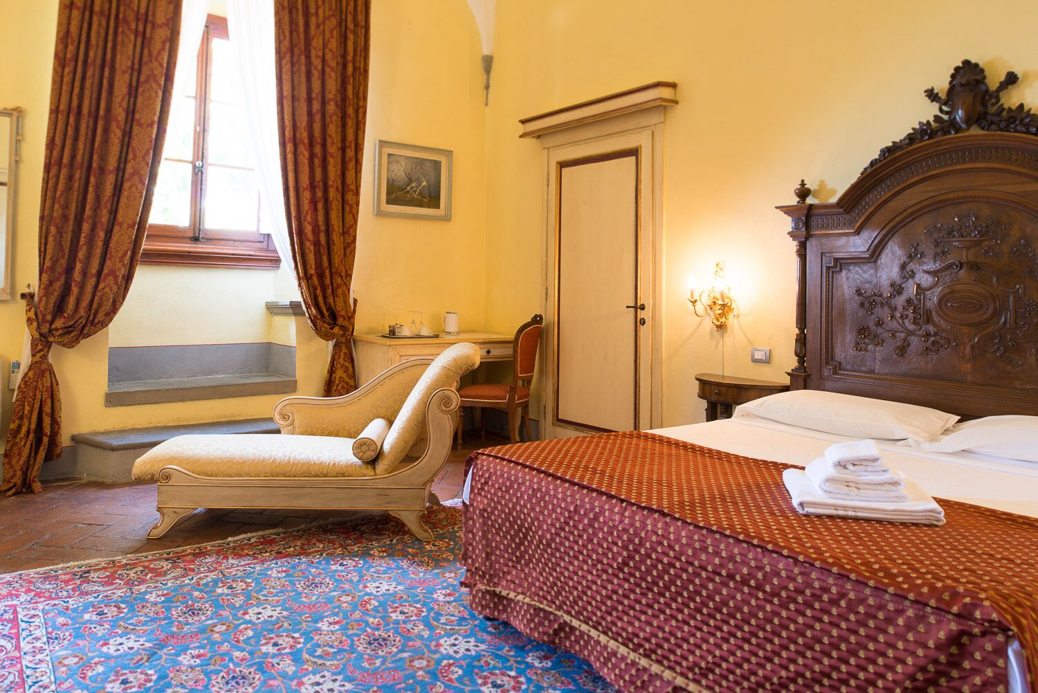 Ein Hotelzimmer mit Bett, Stuhl, Schreibtisch, Kleiderschrank und einem Fenster mit Vorhängen.