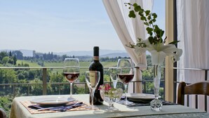 Ein Tisch für zwei, gedeckt mit Weingläsern und einer Weinflasche, mit Blick auf eine schöne Landschaft.
