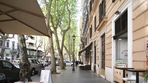 A sidewalk cafe with outdoor seating, trees, and parked cars. - Merulana Star (Rome)