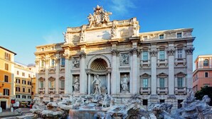 A grand building with a central fountain, featuring classical sculptures and detailed architecture. - Merulana Star (Rome)