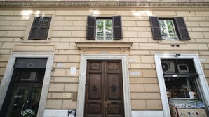 A building facade with a central wooden door marked "1886," flanked by windows with shutters. - Merulana Star (Rome)
