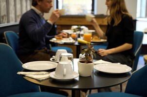 A breakfast setting with a table set for two, including plates, cups, and a small plant.