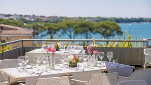 A table set for dining with a view of a body of water and greenery in the background. - Hotel Ristorante Al Fiore (Peschiera del Garda)