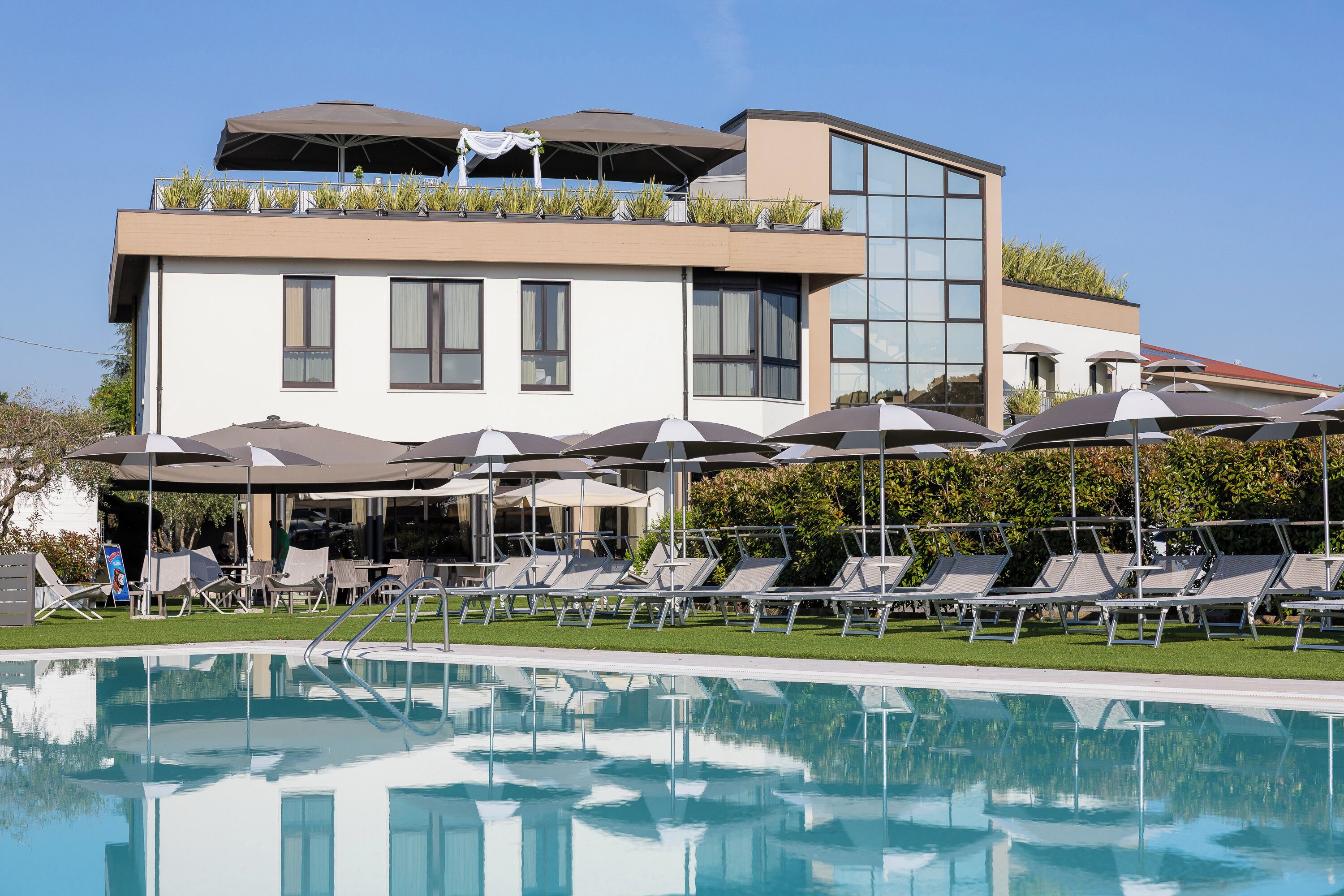 Ein modernes Hotel mit Pool, Liegestühlen und Sonnenschirmen.