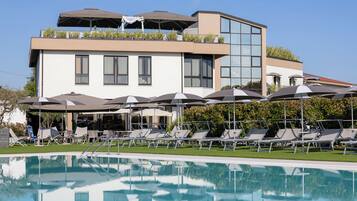 Ein modernes Hotel mit Pool, Liegestühlen und Sonnenschirmen.