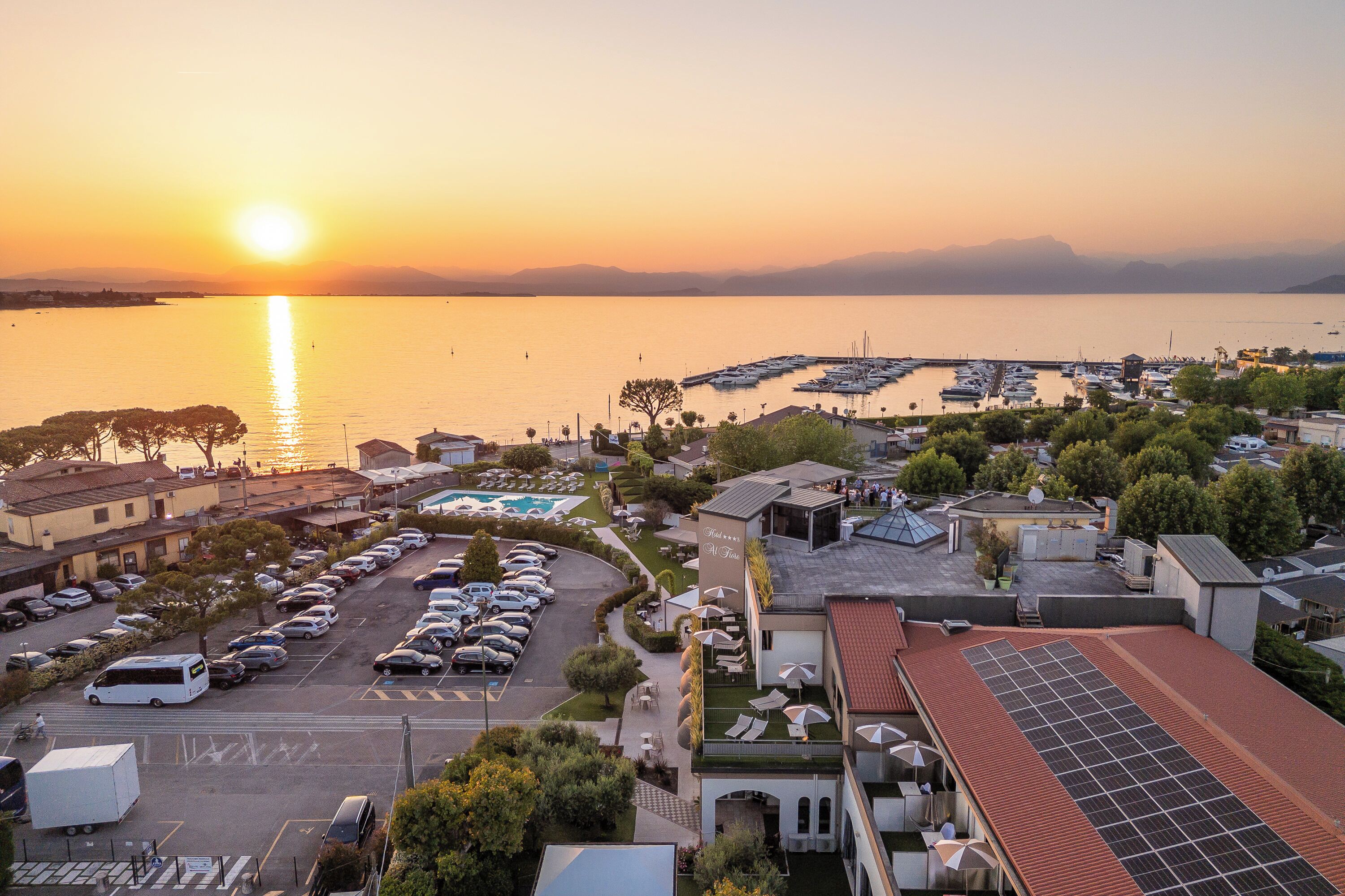 A marina with boats, a parking lot, and buildings with solar panels.