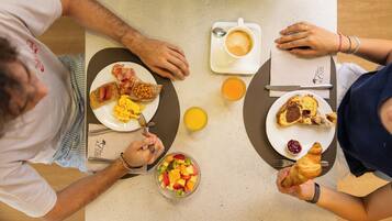 Una mesa con alimentos para el desayuno, como tostadas, huevos y un bol de fruta.