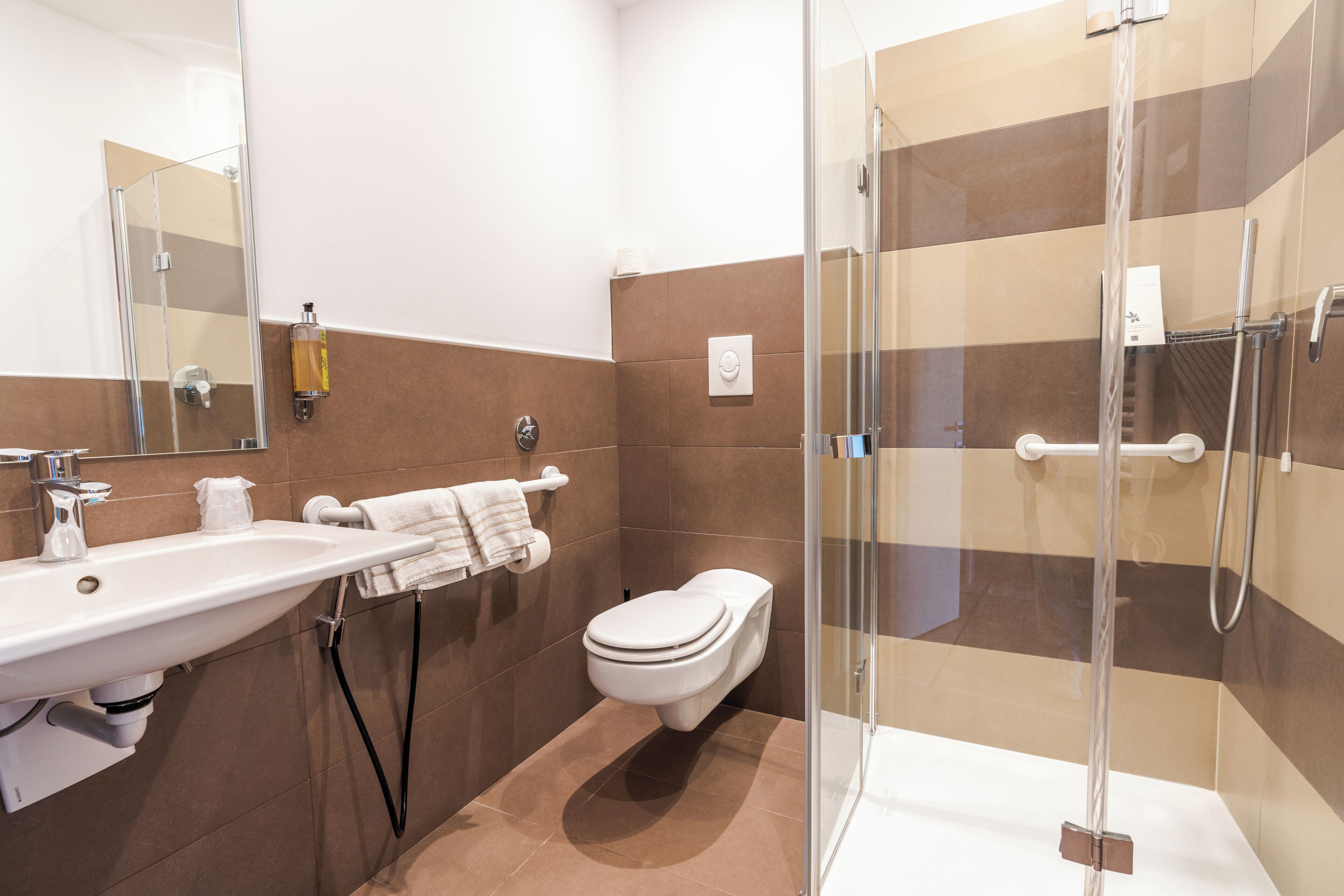 Un baño moderno con ducha de vidrio, lavamanos e inodoro.