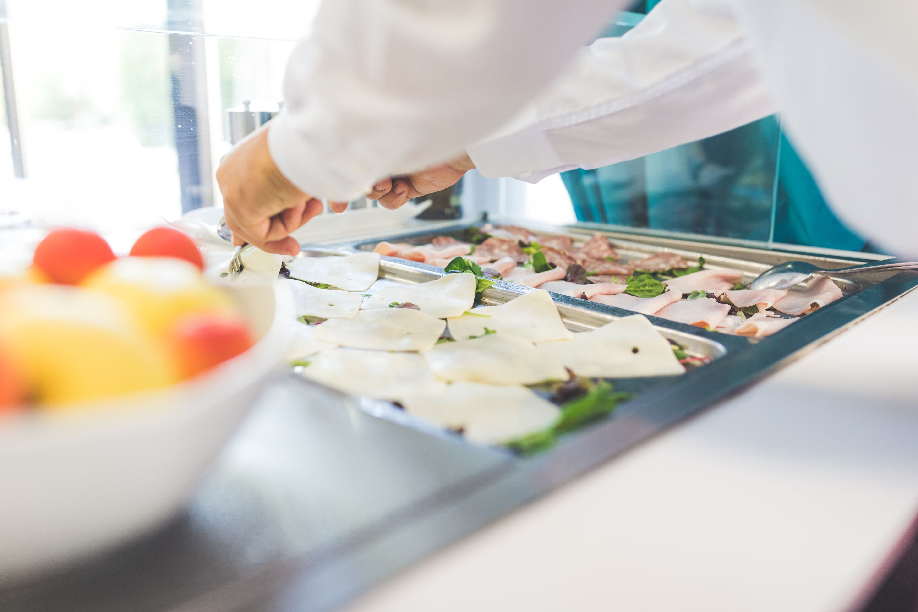 Uno chef prepara del cibo al bancone, con diversi ingredienti e utensili.
